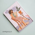 پلنر با طراحی دختر نشسته روی صندلی چوبی، در حال مطالعه یک کتاب، در کنار گلدان و میز چوبی، با پس‌زمینه‌ای ملایم و آرامش‌بخش.
